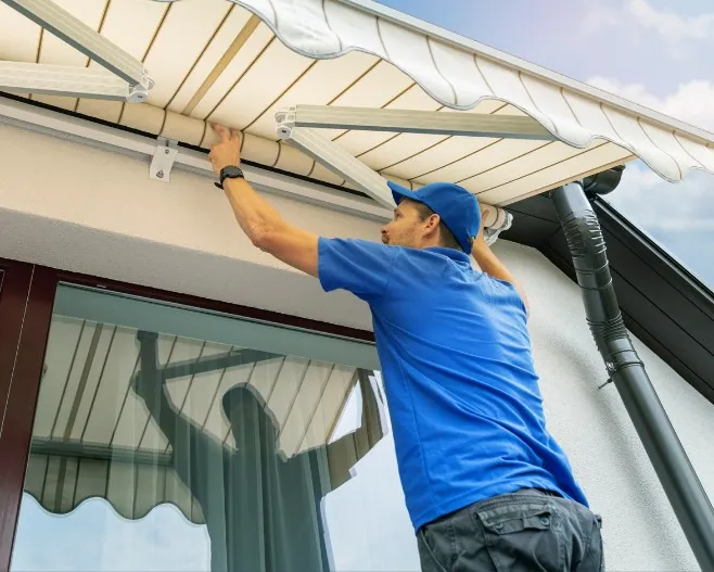 Instalador ajustando el brazo articulado de un toldo sobre la puerta de una terraza