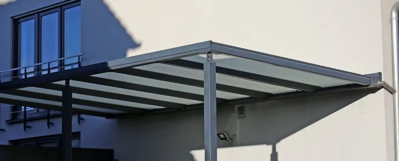 Pérgola de aluminio adosada a fachada Pérgola de aluminio gris adosada a la fachada de una vivienda con la lona de palillería extendida