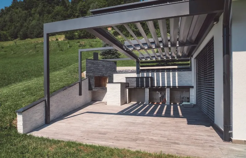 Pérgola bioclimática exenta sobre una cocina exterior con tarima