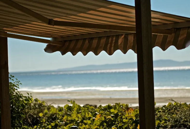 Toldo de brazo articulado en un porche con vistas al mar