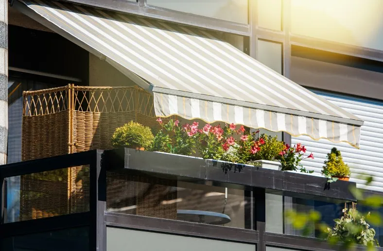 Toldo de brazos con lona a rayas beige en el balcón de una vivienda de Alcantarilla