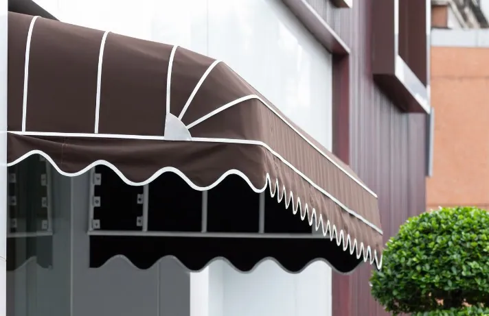 Toldo de capota marrón con volante blanco en la entrada de un comercio