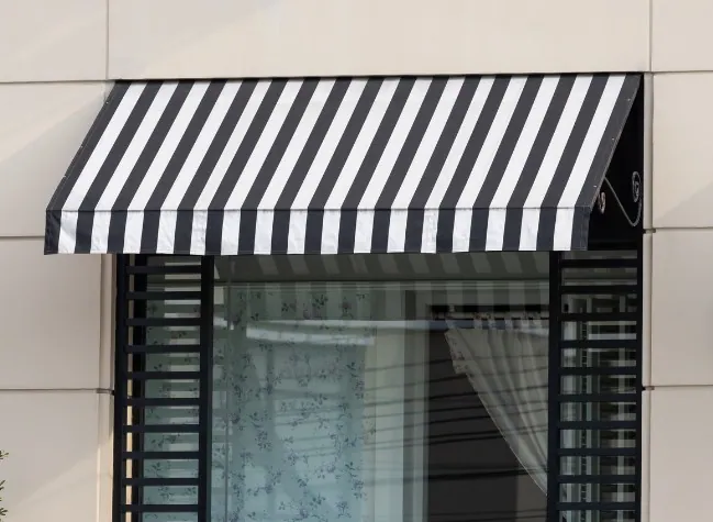 Toldo de capota a rayas negras y blancas sobre la ventana de una fachada