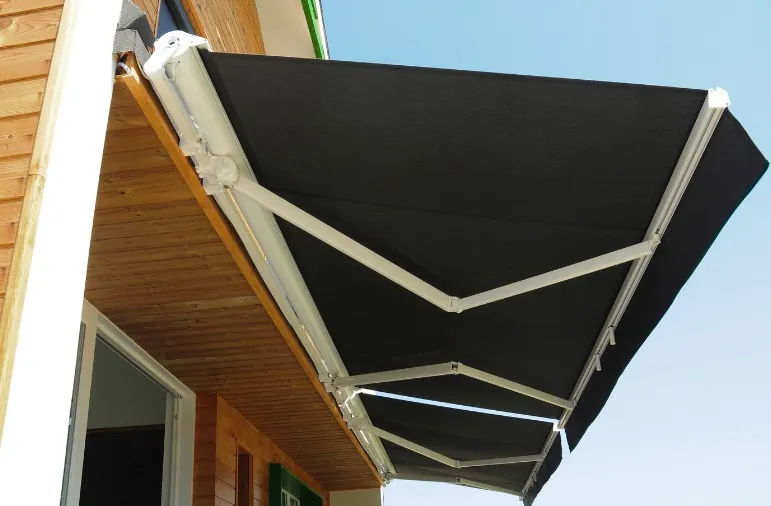 Toldo cofre con lona negra y brazos blancos en la fachada de una vivienda de Beniel