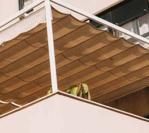 Palillería manual en la terraza de un ático Lona de palillería beige recogida en pliegues sobre una pérgola de aluminio blanca en la terraza de un ático