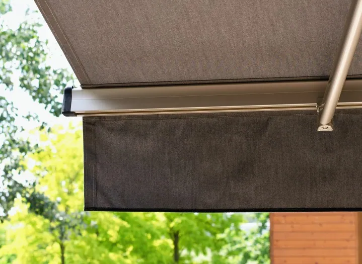 Toldo semicofre con lona gris y faldón sobre un jardín