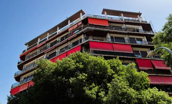 Edificio residencial con toldos rojos del mismo modelo en todos los balcones
